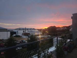 a sunset from a balcony of a building with a parking lot at ROOF TOP 50m2 VUE MER !! à 2 mn à pied de la PLAGE et de la THALASSOTHERAPIE ! in Concarneau