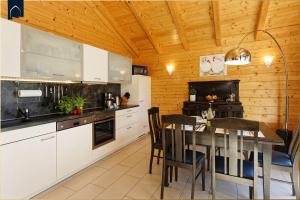 a kitchen with white cabinets and a table with chairs at Ferienhaus Villa Riesling in Zempin +15 photos