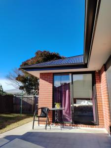 a table and a chair in front of a house at Cosy Sunny Bedroom Close to Airport in Christchurch
