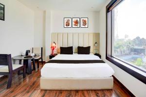 a bedroom with a bed and a desk and a window at Hotel O Golapar Haldwani in Haldwāni
