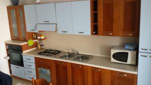 a kitchen with white cabinets and a sink and a microwave at La Macchia in Botrugno