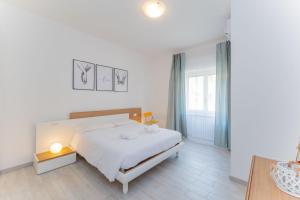 a white bedroom with a bed and a window at Casa Raffaella Comfort e smart working vicino M3 e bus in Milan