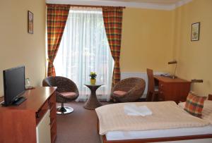 um quarto de hotel com uma cama e cadeiras e uma televisão em Hotel Loucky em Litvínov