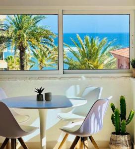 einen Tisch und Stühle in einem Zimmer mit Meerblick in der Unterkunft Penthouse - Beach - Sea View - Pool - 40 sqm Private Terrace - One Bedroom - Sleeping Alcove in Benalmádena