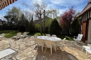 a patio with a table and chairs on a stone patio at Large house with green garden in Tourgeville