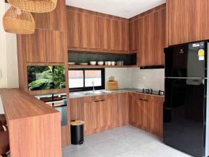 a kitchen with wooden cabinets and a black refrigerator at Pontakorn Villa 1 in Ko Phangan