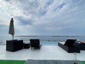 un patio con sombrilla y sillas y el océano en Plazmastay OTARU, en Otaru