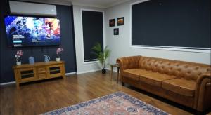 a living room with a brown couch and a flat screen tv at Executive Denman Home in Denman