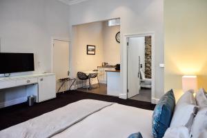 1 dormitorio con 1 cama, TV y escritorio en Three Boutique Hotel, en Ciudad del Cabo