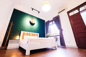 una camera con un letto bianco e una parete verde di Tonkin1987 a Hanoi Altre 23 foto