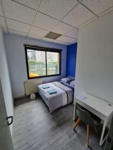 a bedroom with a bed and a desk and a window at Chambre Privée dans appartement partagé BLEU in Toulouse
