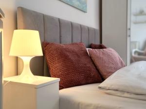 a bed with pillows and a lamp on a table at Tabago Studio 36 Brzeg Chopina in Brzeg +3 photos