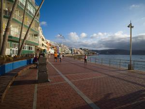 Menschen, die einen gemauerten Bürgersteig neben dem Wasser entlanggehen in der Unterkunft Edison Building By CanariasGetaway in Guanarteme