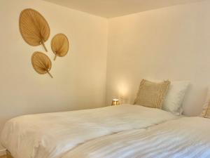 una camera da letto con un letto con lenzuola bianche e ventilatori a parete di Voilà Le Logat - Chambres & Gîtes a Sainte-Gemme
