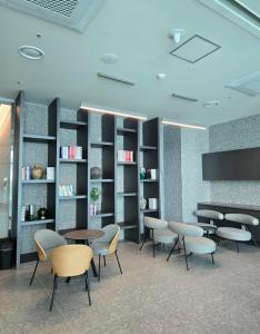 ein Wartezimmer mit Tischen, Stühlen und Bücherregalen in der Unterkunft Ocean GYM n Spa, free parking in Busan