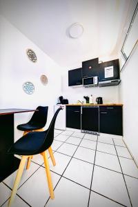 a kitchen with a black chair and a white tile floor at Modernes Studio Appartement im Herzen von Worms in Worms