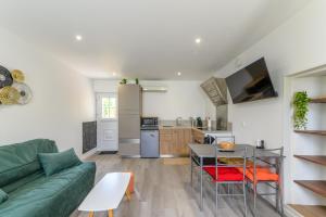 a living room with a green couch and a kitchen at Le Duplex Mouroux - 30min de Disneyland in Mouroux
