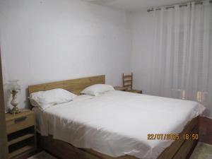 a bedroom with a bed with white sheets and pillows at Casa De Giulio in Cocentaina