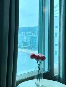 eine Vase mit Blumen auf einem Tisch vor einem Fenster in der Unterkunft Ocean GYM n Spa, free parking in Busan