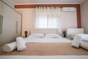 a bedroom with two beds with white sheets and towels at Fjori's Apartments in Sarandë