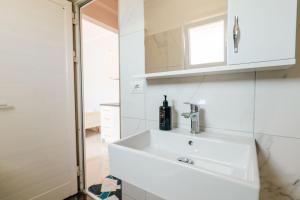 a white bathroom with a sink and a mirror at Fjori's Apartments in Sarandë +40 photos