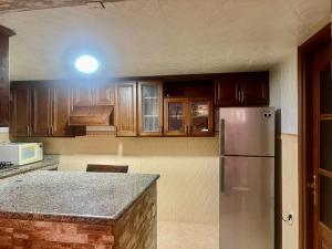 a kitchen with wooden cabinets and a stainless steel refrigerator at Tidal Tranquillity Costal Escape in Asilah