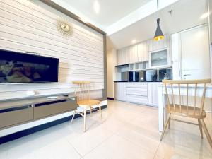 a kitchen with two chairs and a tv on a wall at Charming 2BR Apartment at Amor Pakuwon City Mall East Surabaya by Le Ciel Hospitality in Surabaya