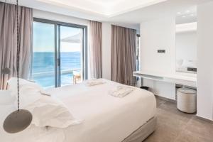 a bedroom with a bed with a view of the ocean at The Royal Blue Andros in Batsi +147 photos