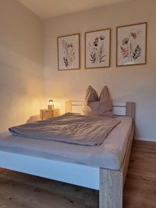 a bed in a bedroom with three pictures on the wall at HofQuartier Altmersleben in Altmersleben