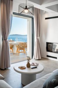 a living room with a table in front of a large window at The Royal Blue Andros in Batsi