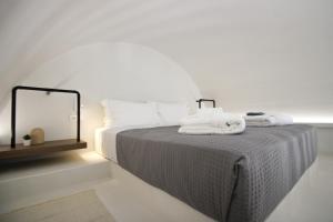 a bedroom with a bed with towels on it at Airy Suites Santorini in Oia