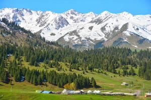 a snow covered mountain range with houses in a field at Syrgak in Dzhergalan