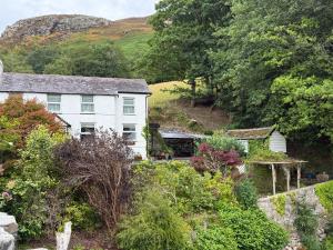 a white house on a hill with trees and bushes at Elegant 4-Bed Pet-Friendly Retreat in Snowdonia in Conwy
