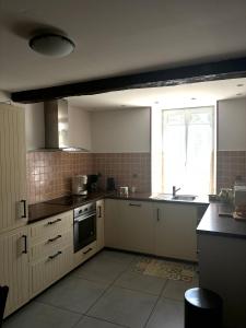 Una cocina con gabinetes blancos y un fregadero y una ventana. en La Maison d'Amélie, en Saint-Fort-sur-Gironde