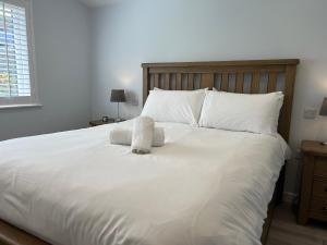 Elle comprend un grand lit avec des draps et des oreillers blancs. dans l'établissement 15 Golden Bay Holiday Village - Coastal Retreat with Breathtaking Views, à Westward Ho