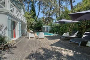 a patio with chairs and an umbrella and a pool at Calme absolu détente en famille & Piscine chauffée in La Tremblade