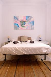 Una cama en un dormitorio con un cuadro en la pared. en Melosas Loft - HOME RENT MALAGA, en Torre del Mar