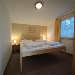 una camera da letto con un letto con lenzuola bianche e una finestra di Campingplatz & Bungalowdorf am Waldbad a Erlau