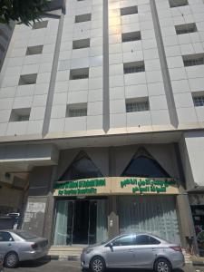 Dos coches aparcados delante de un edificio en فندق مسار الأمل الذهبي - أثمان سابقاً, en Al ‘Azīzīyah