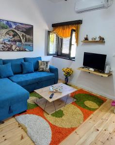 a living room with a blue couch and a table at Sweet Home Aria in Çorovodë