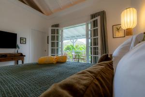a bedroom with a bed with a couch and a window at 1493 lodge de charme le NINA in St Barthelemy