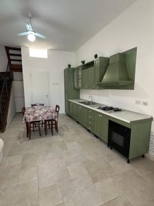 a kitchen with green cabinets and a table and a dining room at BRUNETTI HOLIDAY due in Torre Ovo