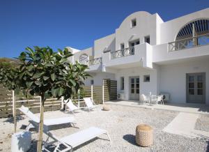 a large white house with chairs and a tree at Airy Suites Santorini in Oia