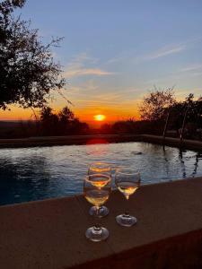 two wine glasses sitting on a table next to a pool at Quinta do Miradouro in Portalegre