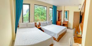 two beds in a room with two windows at Cảnh Tuyền Hotel View Lan Ha Bay in Cat Ba