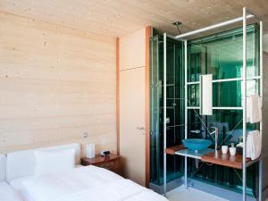 达沃斯Hotel Ochsen by Mountain Hotels的一间带玻璃淋浴间和一张床的卧室