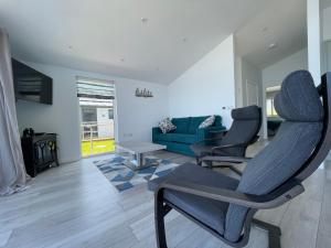 un salon avec un canapé bleu et des chaises dans l'établissement 15 Golden Bay Holiday Village - Coastal Retreat with Breathtaking Views, à Westward Ho