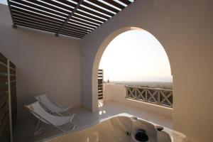 a bath tub in a bathroom with an arched window at Airy Suites Santorini in Oia +82 photos