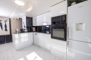 a white kitchen with white cabinets and black appliances at Duplex suite 50m de la plage Carré d'Or Nice in Nice +11 photos