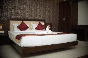a bedroom with a large bed with red pillows at Rajathadri Palace Hotel Lake Breeze Suites in Bengaluru